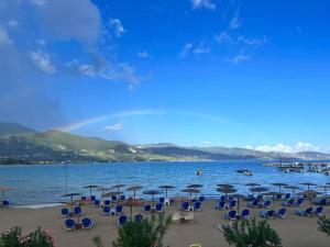 einen Strand mit Stühlen und Sonnenschirmen und dem Wasser in der Unterkunft Agia Kiriaki Bungalows in Alikanas