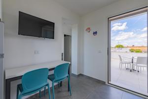 een woonkamer met een tafel en stoelen en een televisie bij Peninsula Apartments in Porto Cesareo