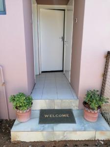 una señal de bienvenida frente a una puerta con dos macetas en Country Block, en Gaborone