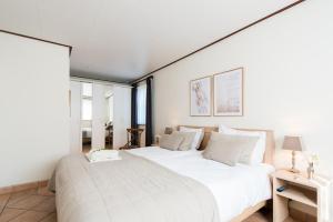 a white bedroom with two beds and a window at Villa met grote tuin in de duinen nabij het strand in Buren