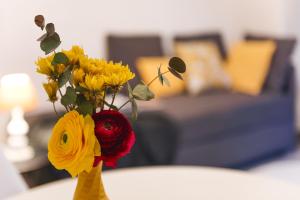un vase rempli de fleurs jaunes et rouges sur une table dans l'établissement DOMUSBERGAMO - Bon bon Apartment, à Bergame