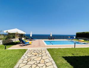 a pool with a umbrella and chairs and the ocean at Villa Korfos in Skala