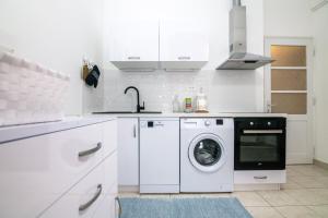a white kitchen with a washing machine and a sink at Apartments Kinkela in Opatija