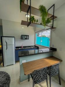 una cucina con tavolo e frigorifero di Mangata Loft - Requinte e Conforto para Lazer ou Trabalho a Itanhaém