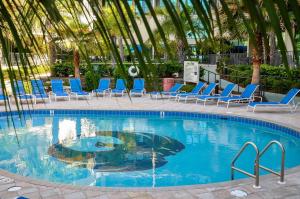 una piscina con sillas azules y palmeras en Phoenix on the Bay by Brett Robinson Vacations, en Orange Beach