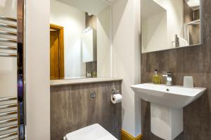 a bathroom with a sink and a toilet and a mirror at Brooklands Guest House in Penrith