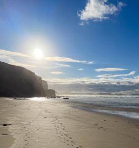 una playa con huellas en la arena y el océano en Atlantic Lodge en Newquay
