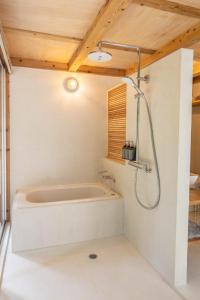 a bathroom with a tub and a shower at SHINMINKA Villa JANADO - Vacation STAY 66320v in Kumejima