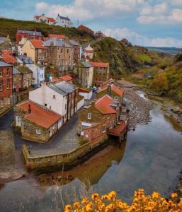 a group of buildings on a hill next to a river at The Blue Porch Staithes in Staithes