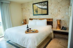 a hotel room with a bed with a tray of food on it at El Taj Oceanfront and Beachside Condo Hotel in Playa del Carmen +37 photos
