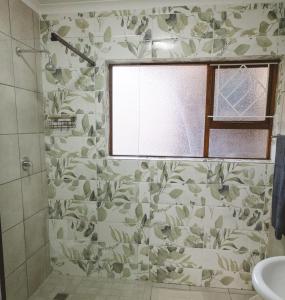 a bathroom with a shower with a floral patterned wall at Habitat Place in Bloemfontein