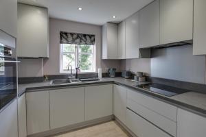 eine Küche mit weißen Schränken und einem Fenster in der Unterkunft Entire home/flat perfect for contractors in Bishops Stortford