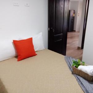 een slaapkamer met een bed met een rood kussen bij Los Cauces familiar y central in Medellín