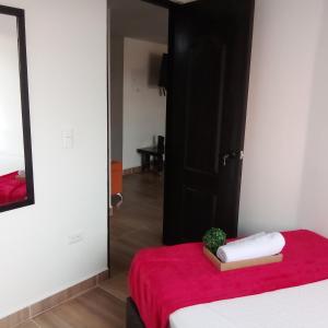 een kamer met een bed met een rode deken en een spiegel bij Los Cauces familiar y central in Medellín