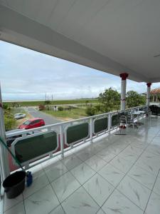 a balcony with a view of the ocean and a car at Zeedijk Resort Nickerie in Nieuw Nickerie
