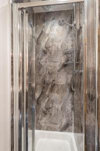 a bathroom with a shower with a white tub at Brooklands 5 Star Guest House in Penrith +53 photos