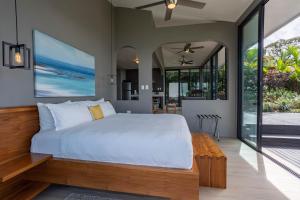 a bedroom with a large white bed and sliding glass doors at Rancho Pacifico - Boutique Hotel for Adults in Uvita
