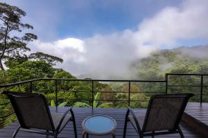 a balcony with two chairs and a view of a mountain at Rancho Pacifico - Boutique Hotel for Adults in Uvita