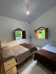 a bedroom with two beds and two windows at Terra Hostel e Pousada in Lençóis