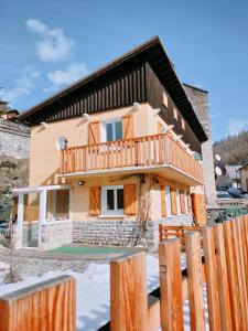 a house with a wooden deck in the snow at Gite Notre Désir in Abriès