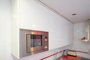 um micro-ondas de aço inoxidável numa cozinha com paredes brancas em Bonito, Práctico y muy bien comunicado em Madri