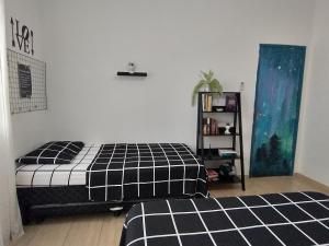 リオデジャネイロにあるEspaço Agradável, Rio de Janeiroのベッドルーム(白黒のベッド1台、本棚付)