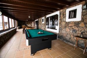 una mesa de billar en una habitación con una pared de piedra en Villa Numama, en Puerto del Rosario