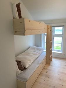 a bedroom with a wooden bunk bed with a window at Storlauvøya The Atlantic Ocean Road in Karvåg