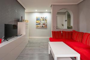 uma sala de estar com um sofá vermelho e uma televisão em Bonito, Práctico y muy bien comunicado em Madri