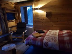 1 dormitorio con 1 cama y 1 silla en una cabaña en Studio l'Étoile, en Saint-Jean-dʼArves