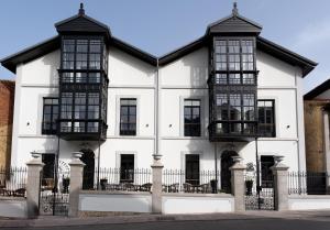 a white building with black windows and a fence at Hotel Boutique Las Indianas in Nueva de Llanes