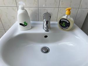 - un lavabo dans la salle de bains avec 2 bouteilles de détergent et un savon dans l'établissement H&H Studio-Apartments im Zentrum jedes Apartment mit Küchenzeilen - 24h Check In, à Greifswald