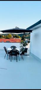 a patio with tables and chairs under a black umbrella at MURIC Apartman 8 in Ljubljana