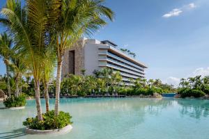 a swimming pool with palm trees in front of a building at Impression Moxché by Secrets - Adults Only in Playa del Carmen