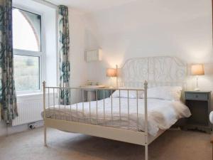1 cama blanca en un dormitorio con ventana en Chambercombe Villa - Harbour View, Decking, Garden, Games Room, sleeps 20, en Ilfracombe