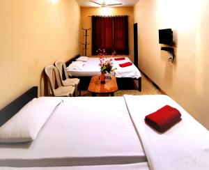 a hotel room with two beds and a table with flowers at Mandarin Hotel Mapusa in Mapusa