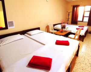 a room with three beds with red pillows on them at Mandarin Hotel Mapusa in Mapusa