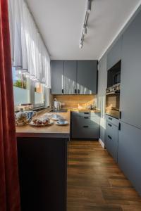a kitchen with black cabinets and a wooden floor at Apartament Pod Dwójką in Bielsko-Biała
