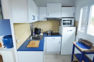 a white kitchen with a sink and a refrigerator at Alamic in Grimaud