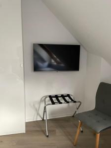 Cette chambre dispose d'une chaise et d'une télévision murale. dans l'établissement H&H Studio-Apartments im Zentrum jedes Apartment mit Küchenzeilen - 24h Check In, à Greifswald