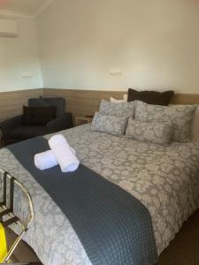 1 dormitorio con 1 cama grande y 1 silla en Merriwa Golden Fleece Motor Inn & Lodge incorporating Merriwa Motor Inn & Motel en Merriwa