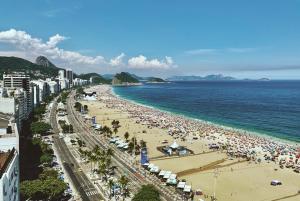 una playa con mucha gente y el océano en Modern Apartment perto 1 block Copacabana Beach best beach - Rio Janeiro en Río de Janeiro
