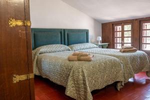 a bedroom with two beds with green bedspread and towels at Dehesa Vieja Casa Rural in Alarcón