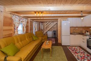 a living room with a yellow couch and a kitchen at Rustic house in Kolašin