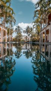 uma piscina de água em frente a um edifício com palmeiras em Villa Canziani & Donato em Pôrto de Pedras