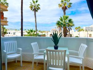 una mesa y sillas en un balcón con palmeras en Miss Flora playa honda, en Playa de las Américas