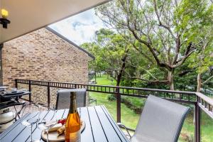 a table with a bottle of wine on a balcony at Bay Parklands, 36 2 Gowrie Avenue - close to the water with Air con, WiFi, pool & spa & tennis court in Shoal Bay