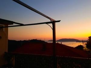 La Terrazza sul Golfo dei Poeti tra Lerici e le Cinque Terre في Pitelli: غروب الشمس على الماء مع ضوء الشارع