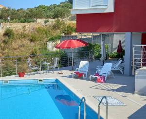 einen Pool mit Stühlen und einem roten Regenschirm in der Unterkunft Luxury Apartments Villa Lenka in Podstrana