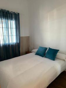 ein Schlafzimmer mit einem großen weißen Bett mit blauen Kissen in der Unterkunft Casa Suso in El Remo